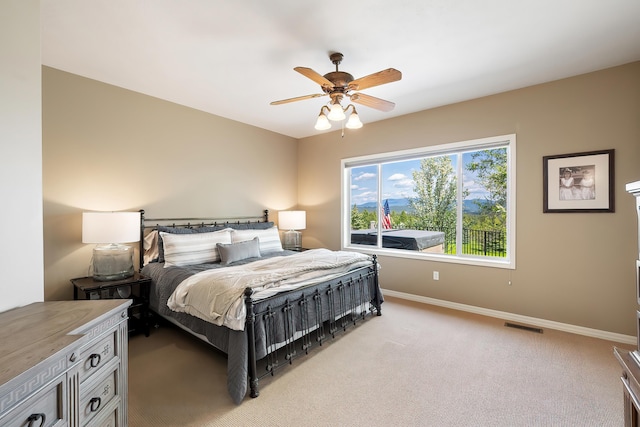 bedroom featuring baseboards, a ceiling fan, visible vents, and light carpet