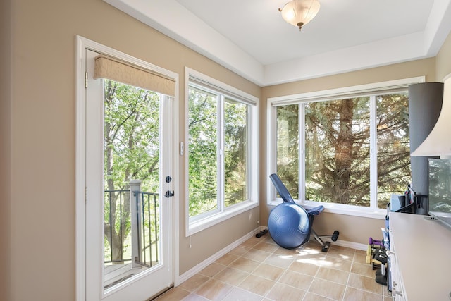 sunroom with a healthy amount of sunlight, tile patterned floors, and baseboards