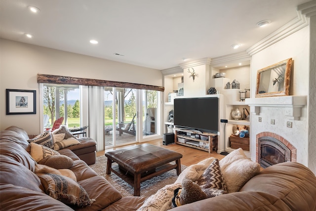living area with visible vents, recessed lighting, light wood-style flooring, and a glass covered fireplace