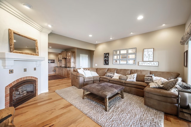 living room featuring recessed lighting, light wood-style flooring, and a fireplace
