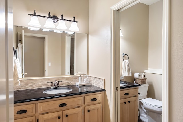 bathroom with vanity, decorative backsplash, and toilet