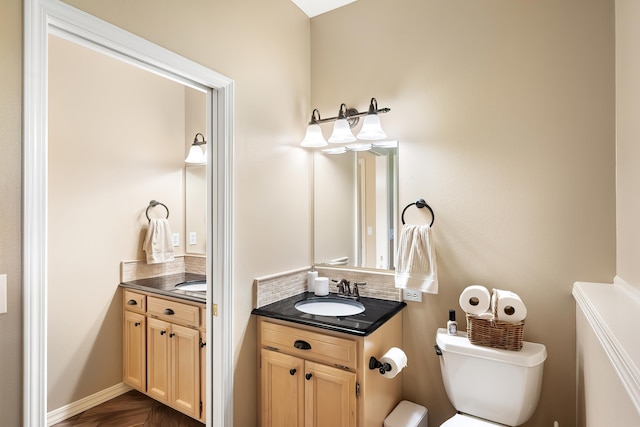 half bathroom with vanity, toilet, and tasteful backsplash