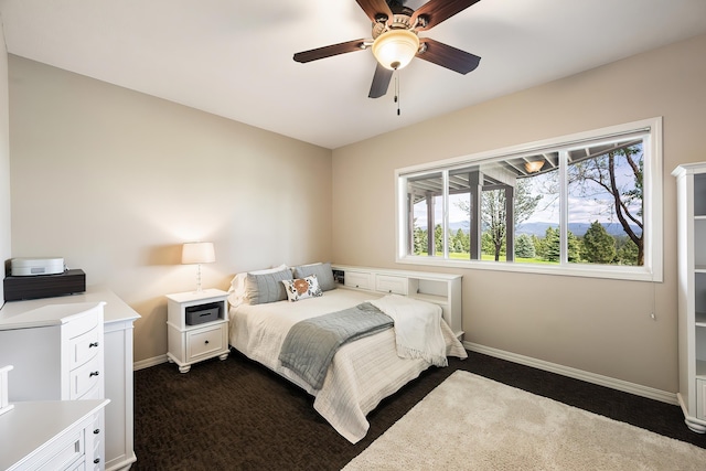 bedroom with dark colored carpet, a ceiling fan, and baseboards