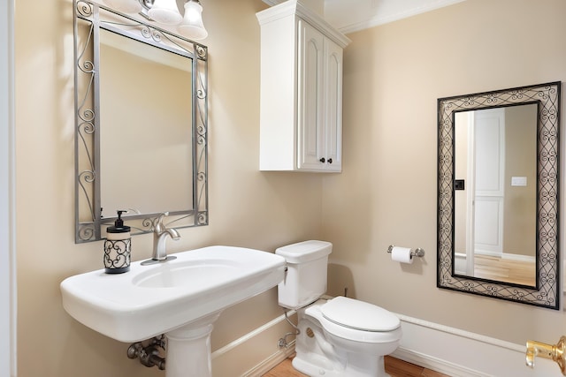 bathroom with toilet, baseboards, and wood finished floors