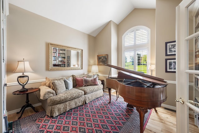 sitting room featuring baseboards, wood finished floors, and high vaulted ceiling