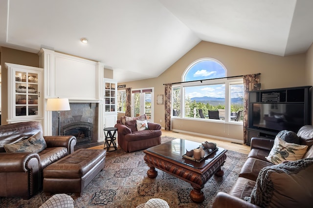 living area with light wood-style floors, high vaulted ceiling, and a fireplace