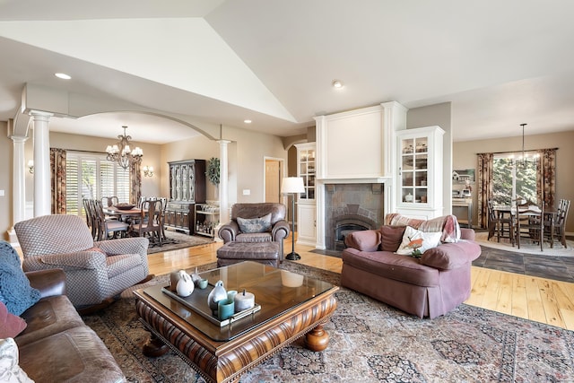 living area with an inviting chandelier, arched walkways, decorative columns, and wood finished floors