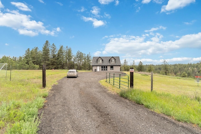 view of street featuring a forest view, a rural view, a gated entry, and dirt driveway