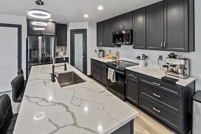 kitchen with a sink, appliances with stainless steel finishes, dark cabinetry, and decorative light fixtures
