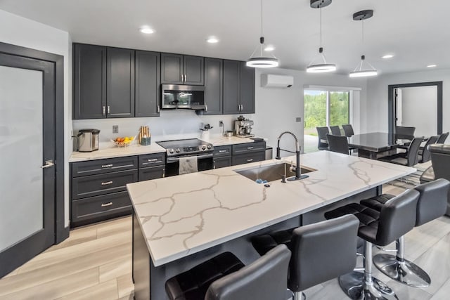 kitchen with a breakfast bar, open floor plan, a wall unit AC, a sink, and stainless steel appliances