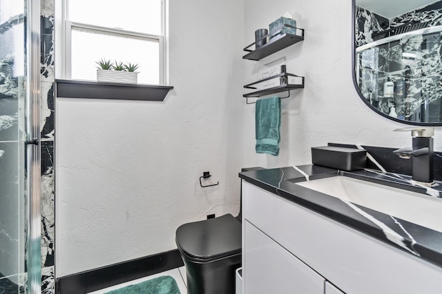 full bath with vanity, a textured wall, a shower with shower door, and toilet