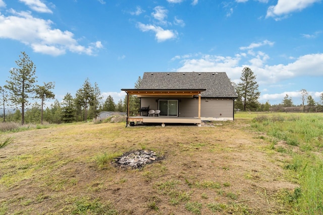 back of property with a lawn, a wooden deck, and roof with shingles