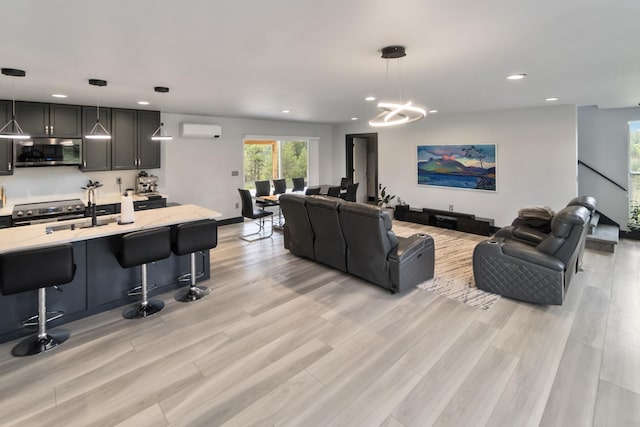 living room featuring recessed lighting, a notable chandelier, light wood-style flooring, and a wall mounted air conditioner