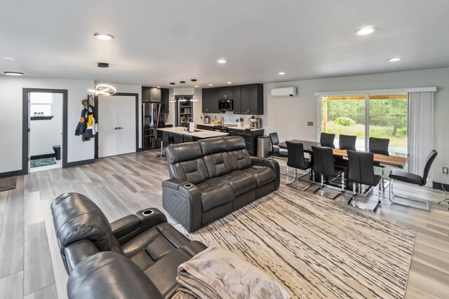 living area featuring a healthy amount of sunlight, light wood-style flooring, and a wall mounted air conditioner