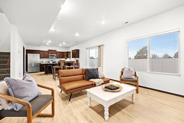 living area featuring visible vents, stairs, baseboards, light wood-type flooring, and recessed lighting
