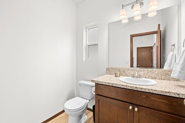 half bath featuring vanity, baseboards, toilet, and wood finished floors