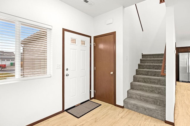 entrance foyer with visible vents, baseboards, light wood finished floors, and stairs