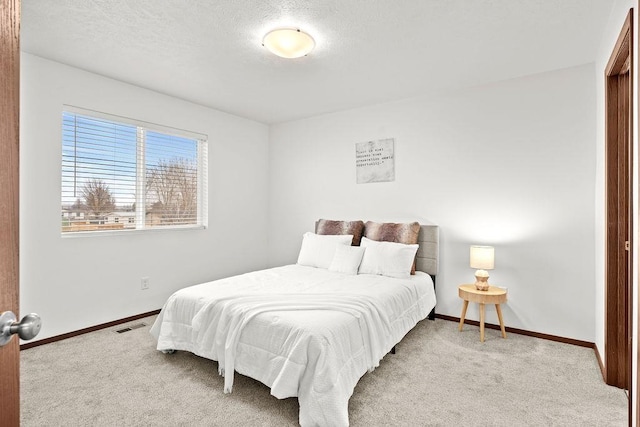 carpeted bedroom with baseboards, a textured ceiling, and visible vents