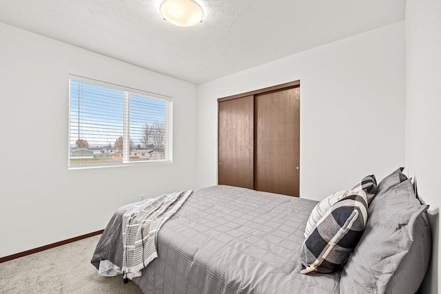 carpeted bedroom featuring baseboards and a closet