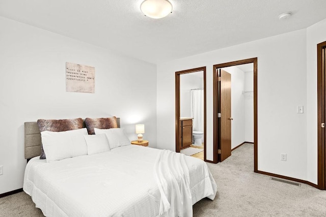 bedroom featuring baseboards, light colored carpet, a walk in closet, and visible vents