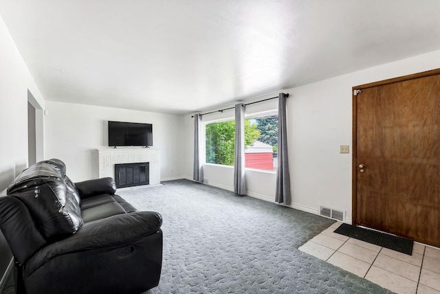 living room featuring light colored carpet, visible vents, a fireplace, light tile patterned floors, and baseboards