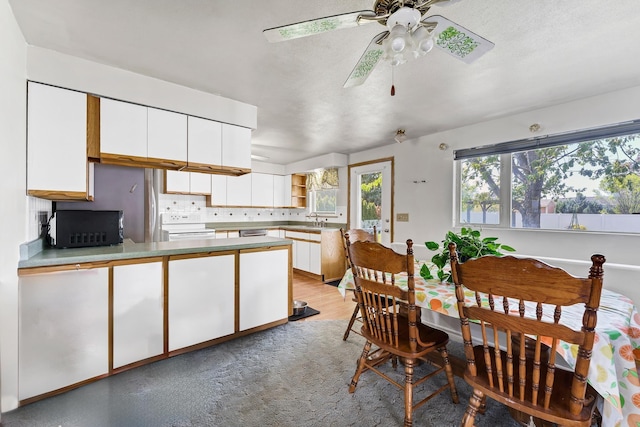 kitchen with tasteful backsplash, white electric range, a sink, a peninsula, and white cabinetry