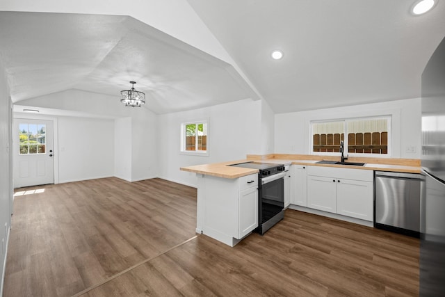 kitchen with a chandelier, a sink, wood counters, appliances with stainless steel finishes, and vaulted ceiling