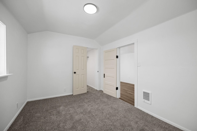unfurnished bedroom featuring visible vents, carpet flooring, baseboards, and lofted ceiling