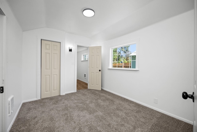 unfurnished bedroom with visible vents, carpet, baseboards, vaulted ceiling, and a closet