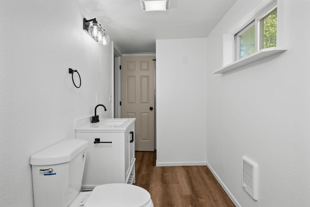bathroom with visible vents, wood finished floors, baseboards, vanity, and toilet