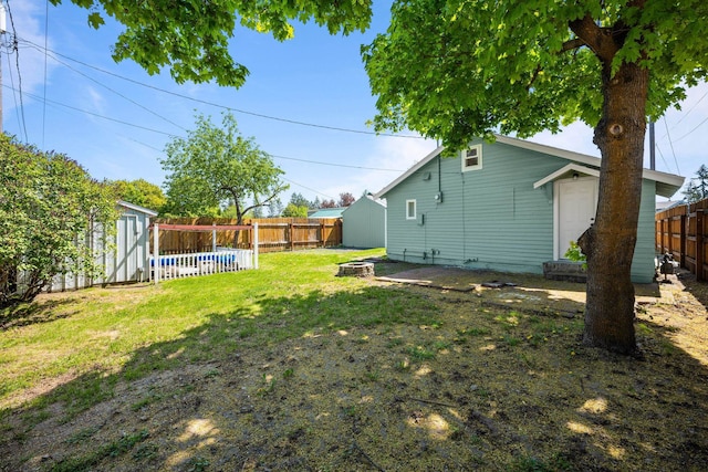 view of yard with an outdoor structure, a fenced backyard, and a storage shed