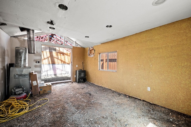 unfurnished living room with a wood stove and vaulted ceiling