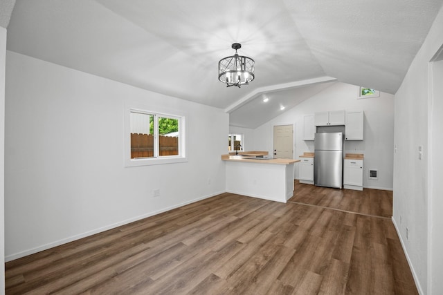 unfurnished living room with an inviting chandelier, a sink, baseboards, lofted ceiling, and dark wood-type flooring