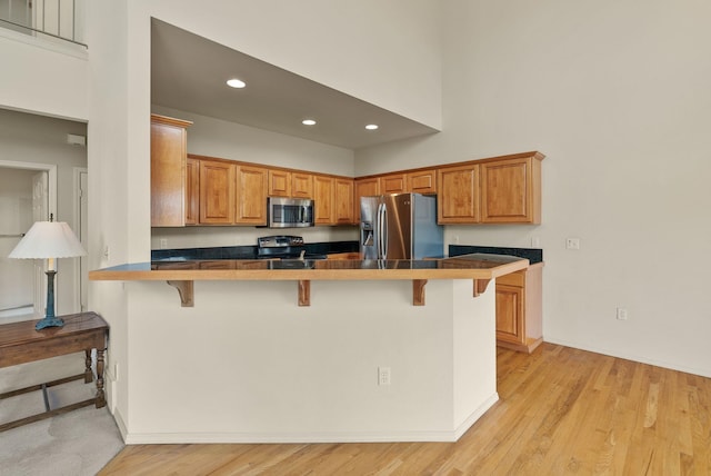 kitchen with recessed lighting, a peninsula, a breakfast bar, and stainless steel appliances