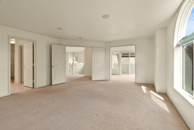 interior space with baseboards, plenty of natural light, and light carpet