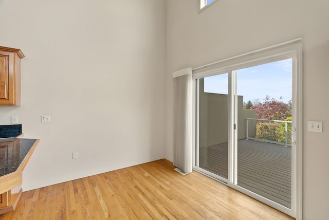 interior space with light wood-type flooring, baseboards, and a high ceiling