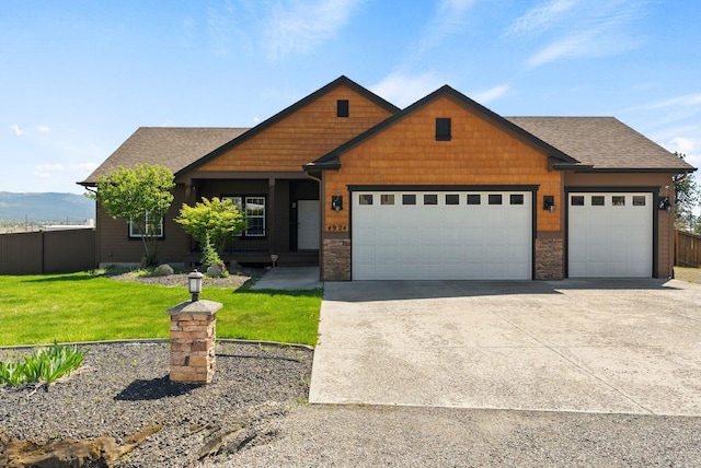 craftsman inspired home with concrete driveway, an attached garage, fence, and a front yard