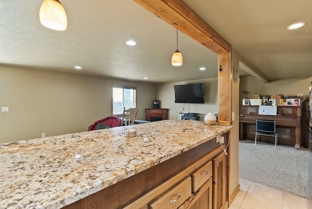 kitchen with light stone countertops, hanging light fixtures, a textured ceiling, recessed lighting, and open floor plan