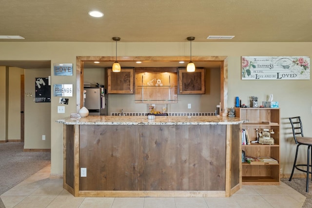 kitchen featuring visible vents, light stone countertops, baseboards, freestanding refrigerator, and recessed lighting