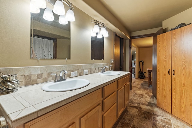 full bathroom featuring double vanity, a sink, decorative backsplash, and stone finish floor