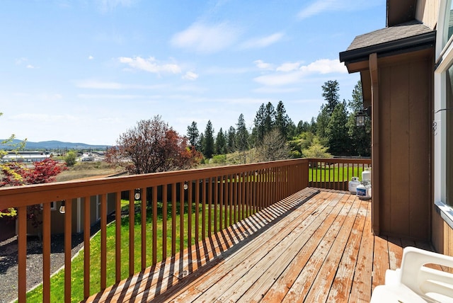 wooden deck featuring a mountain view and a yard
