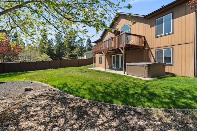 back of property featuring a deck, a fenced backyard, a patio area, a hot tub, and a yard