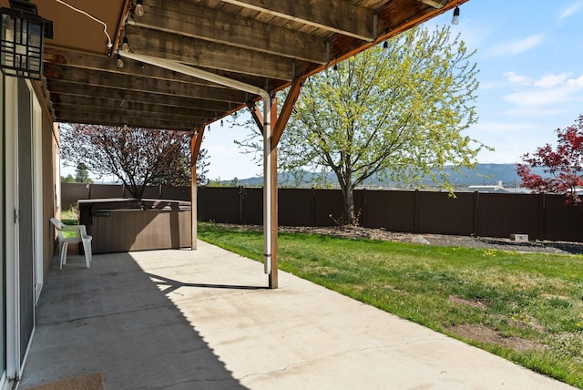 view of patio featuring a fenced backyard, a mountain view, and a hot tub