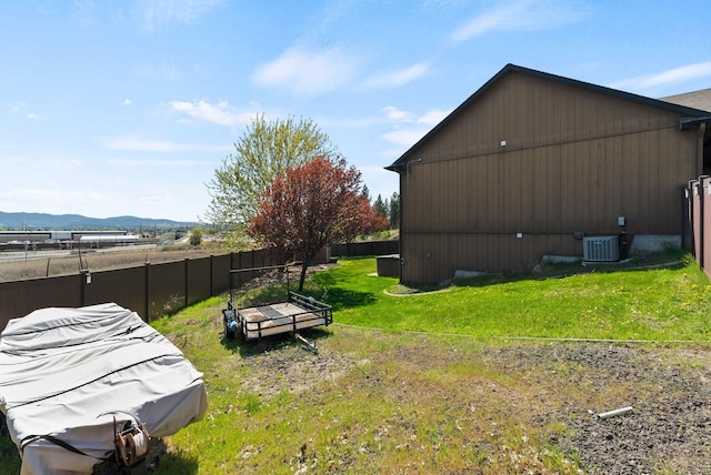 view of yard featuring fence, central AC unit, and a mountain view