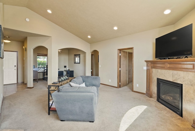 living area featuring arched walkways, lofted ceiling, and light colored carpet