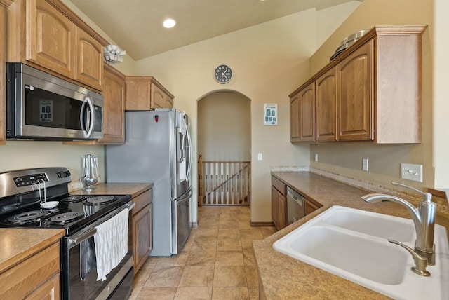 kitchen featuring lofted ceiling, recessed lighting, arched walkways, a sink, and appliances with stainless steel finishes