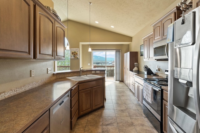 kitchen featuring pendant lighting, lofted ceiling, dark countertops, a sink, and stainless steel appliances
