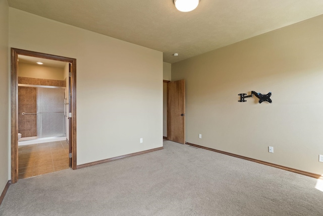 unfurnished bedroom featuring baseboards, carpet flooring, and ensuite bath