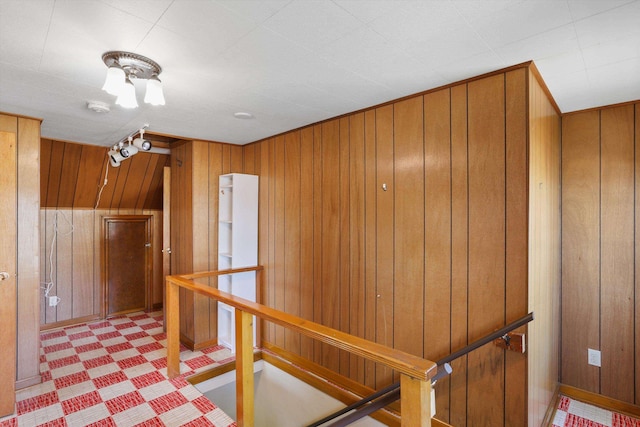 interior space with tile patterned floors, wooden walls, and an upstairs landing