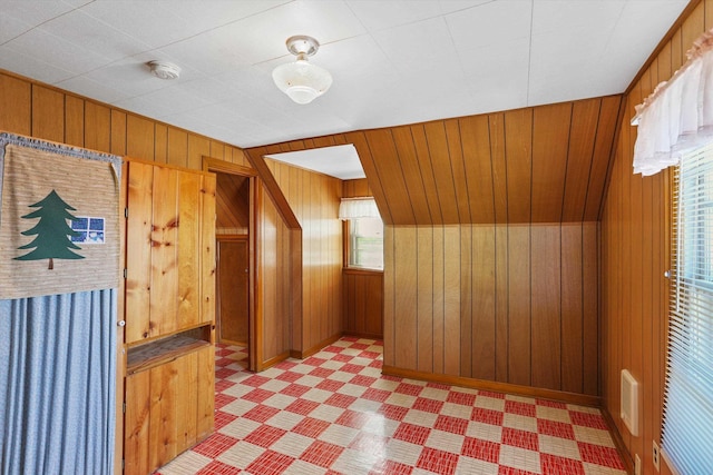 additional living space featuring visible vents, light floors, and wooden walls